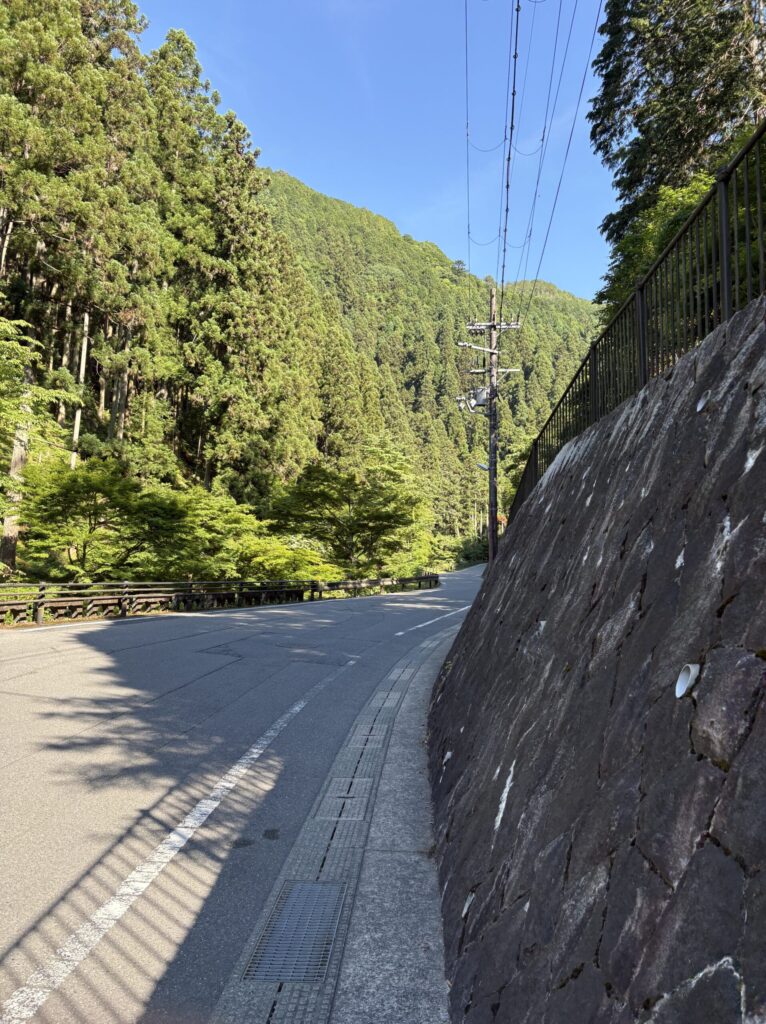 貴船口から貴船神社へ続く山あいの車道。石垣と新緑、青空