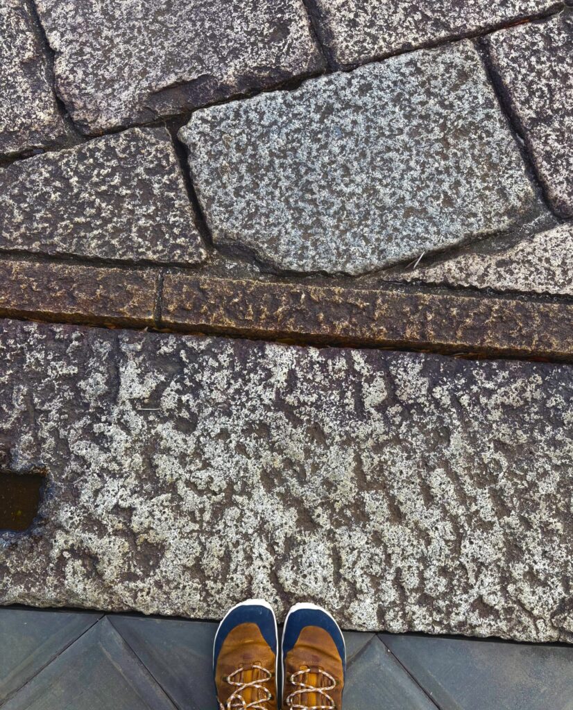 京都の街の石畳を見下ろした一枚。敷石の上に茶色の靴の足元