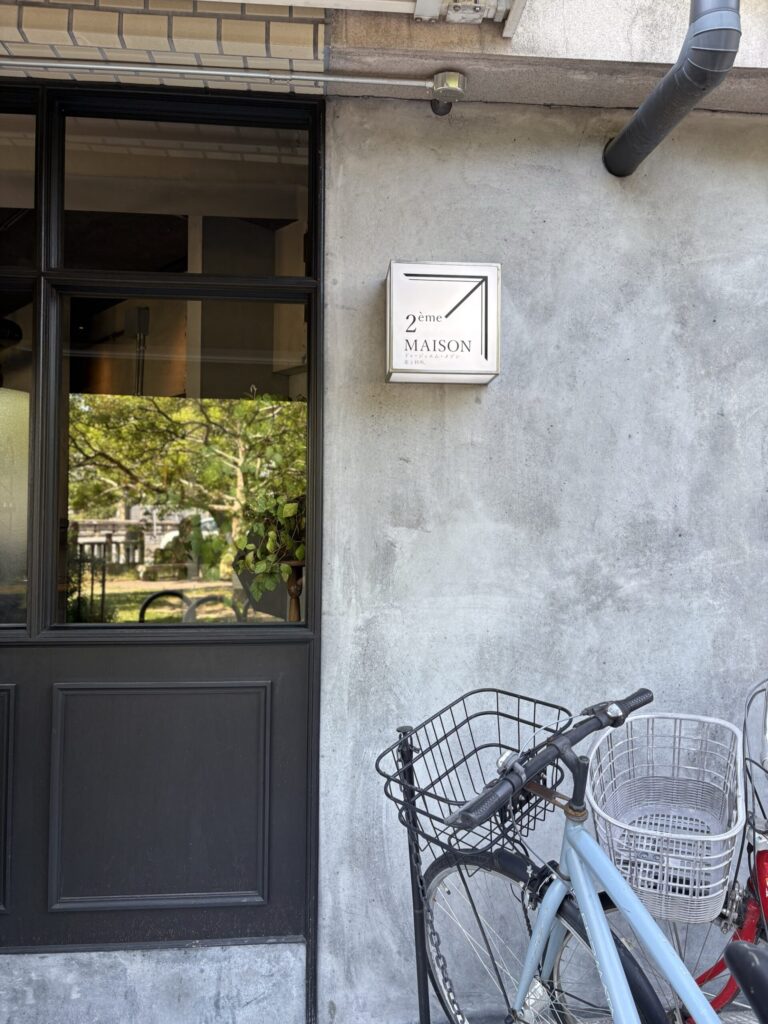 ドゥージィエムメゾンのロゴ看板と、店先に停まる自転車