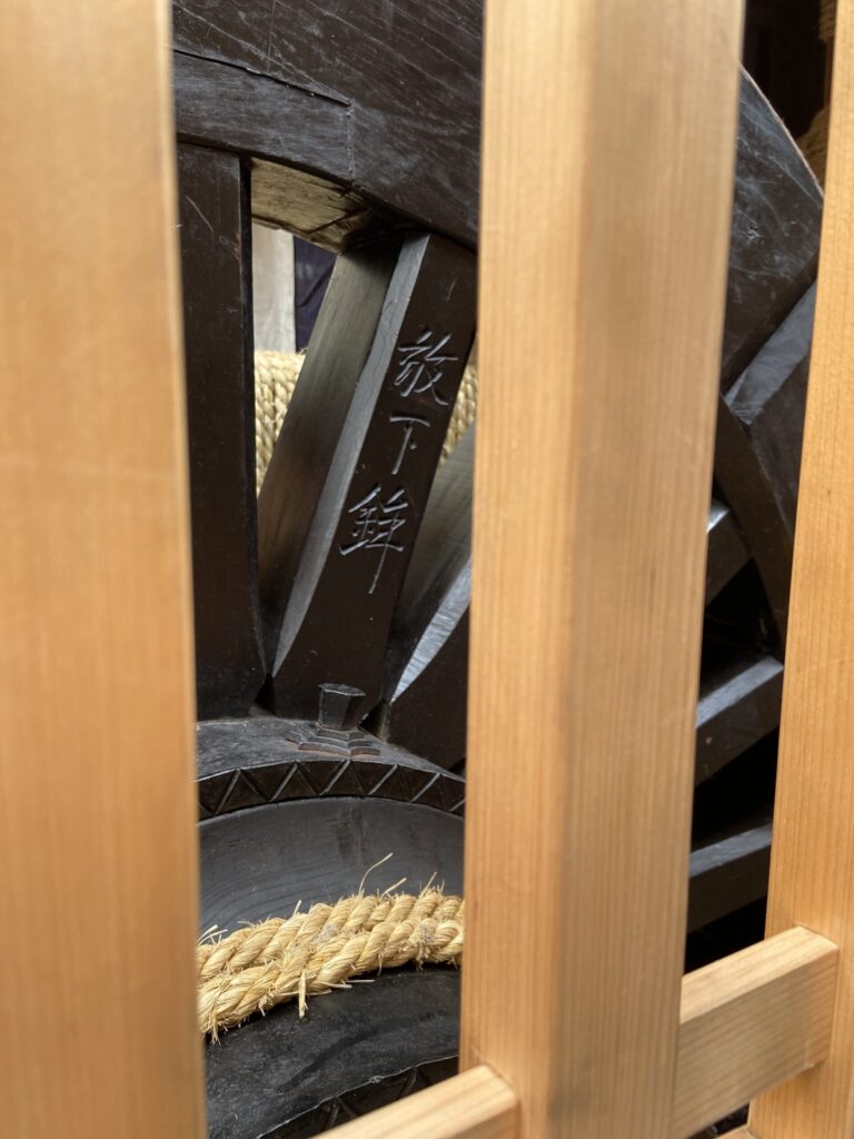 格子越しに見える、祇園祭・放下鉾の木の車輪と縄がらみ