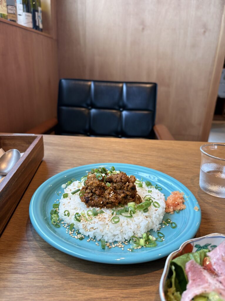 ターコイズブルーの皿の鴨葱キーマカレー。白ごはんに青ねぎと白ごまがまぶされている