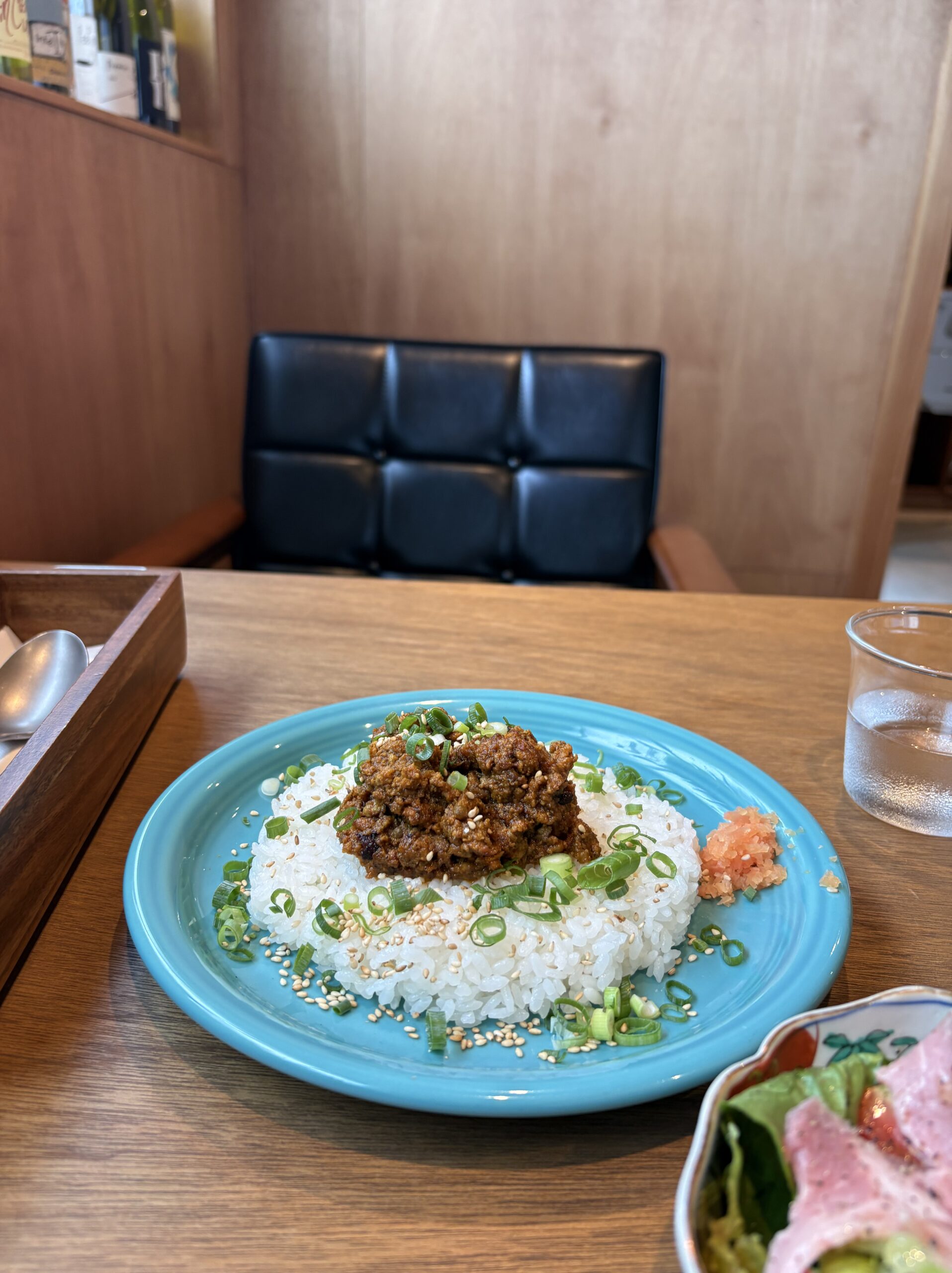 ターコイズブルーの皿の鴨葱キーマカレー。白ごはんに青ねぎと白ごまがまぶされている