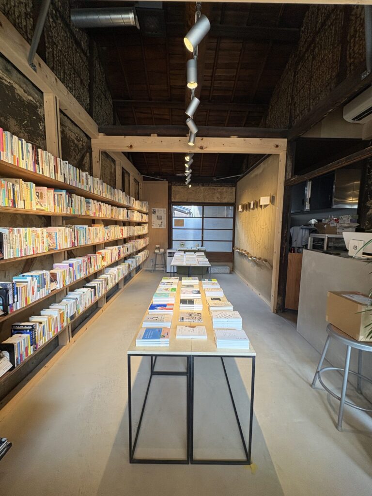 鴨葱書店の店内。町家の梁の下、壁一面の本棚と中央の平台