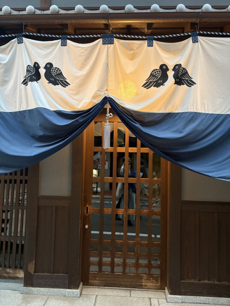 祇園祭 後祭、八幡山の町内の家にかかる鳩の意匠の暖簾と木格子の扉