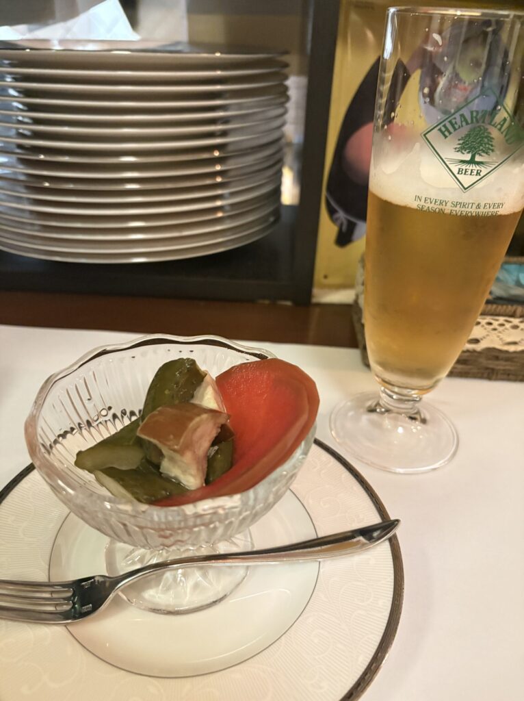 ガラスの器に盛られた自家製ピクルスとビールのグラス