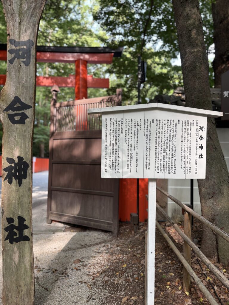 河合神社の入口。朱の鳥居の手前に、由緒を記した白い案内板