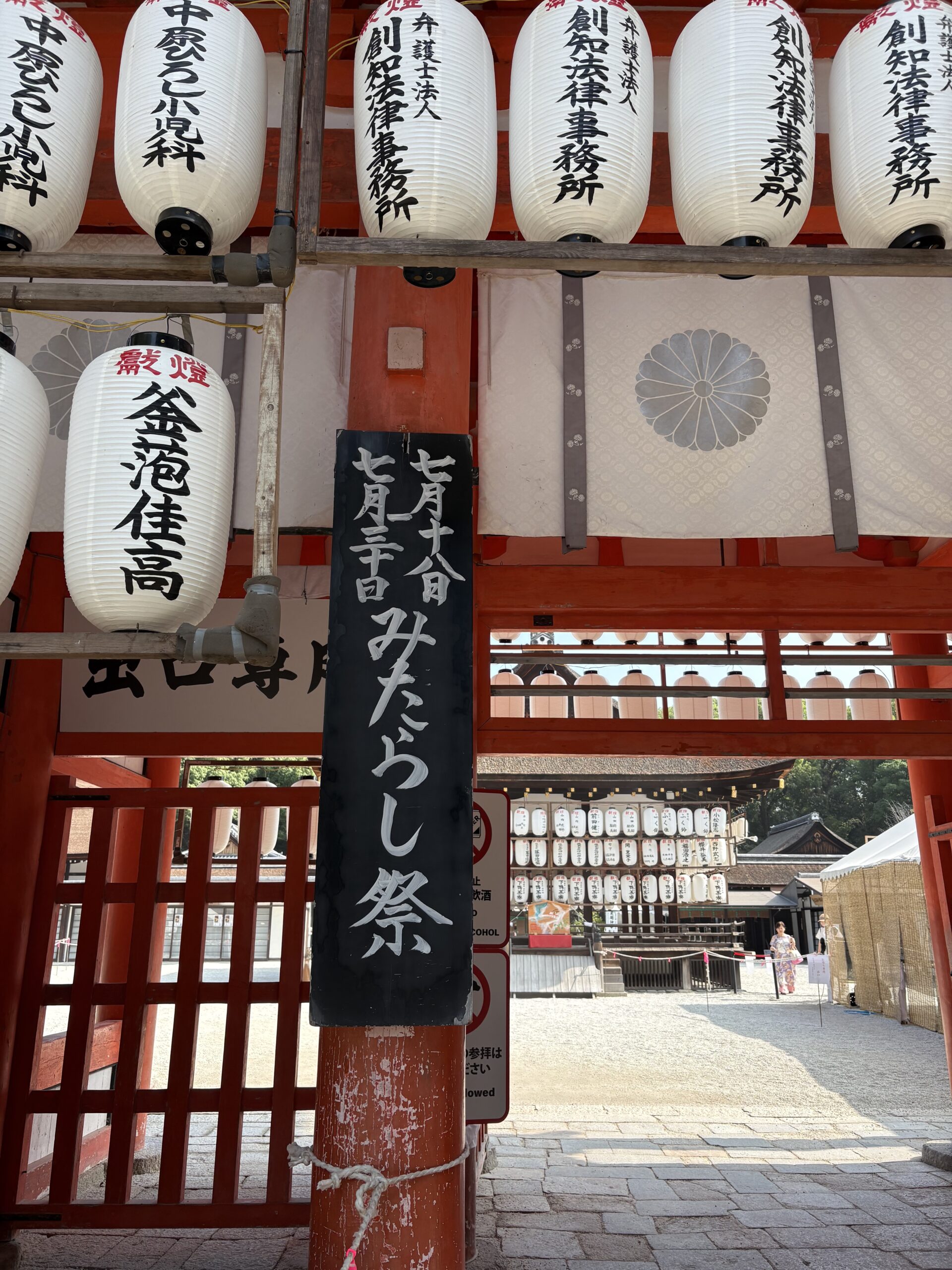 楼門に掛かる「七月十八日 七月三十日 みたらし祭」の黒い立て札と、白い奉納提灯