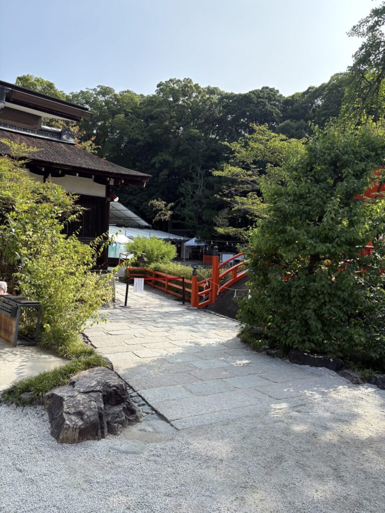 下鴨神社の境内。檜皮葺の建物の奥に朱の輪橋と、祭の白いテントが見える