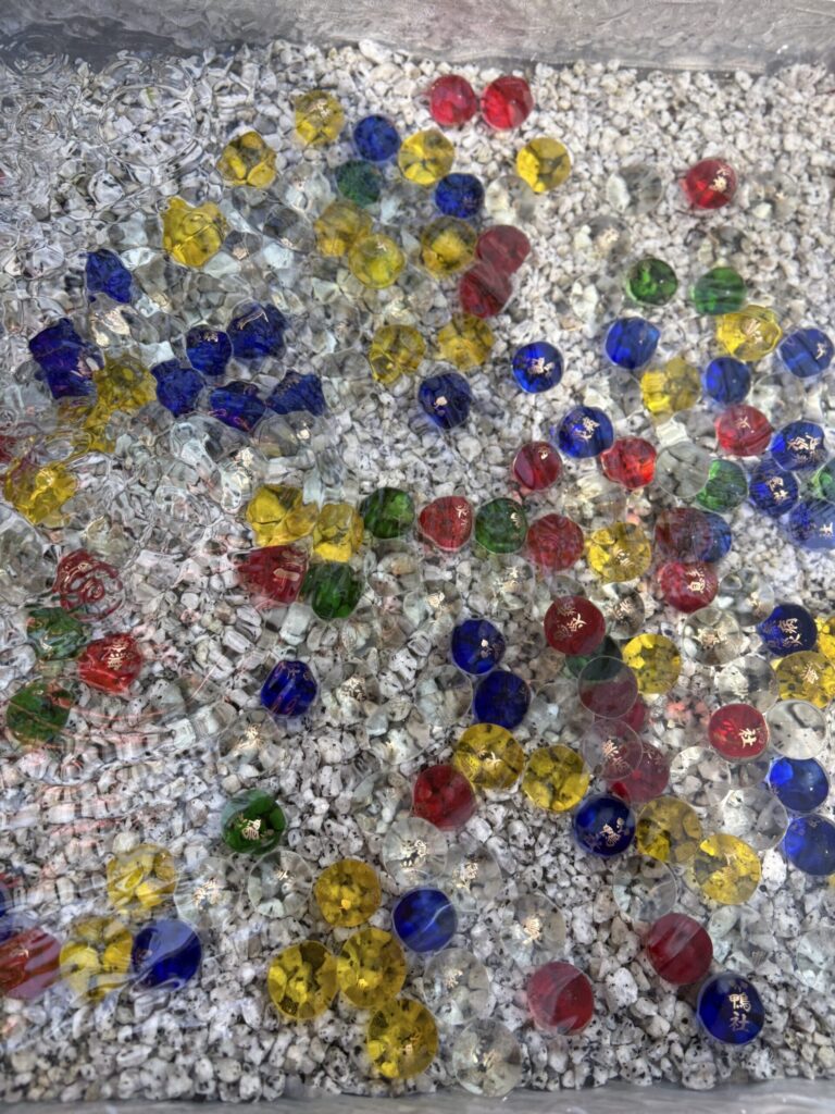 水盤に沈められた色とりどりのガラス玉。金色の文字が入っている