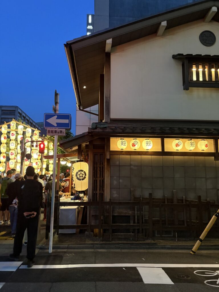 祇園祭 後祭・鈴鹿山の会所前。授与所に人が集まり、通りに提灯が連なる