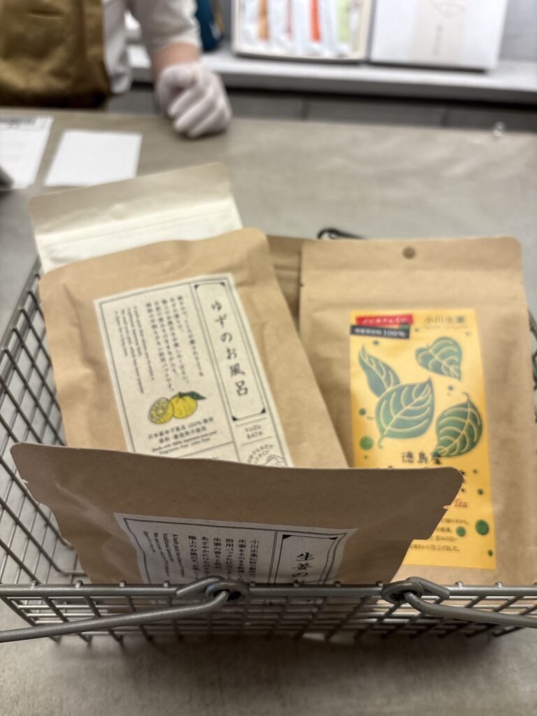 買い物かごに入れたゆずのお風呂と生姜のお風呂、徳島産のお茶