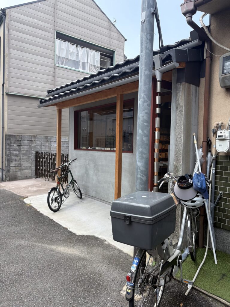 鴨葱書店を通りから。軒先に停まる自転車と、隣家のブロック塀