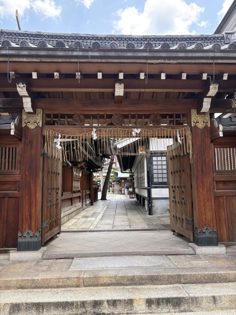 京都ゑびす神社の門。注連縄の下がる木の扉と、奥へ続く石畳の参道