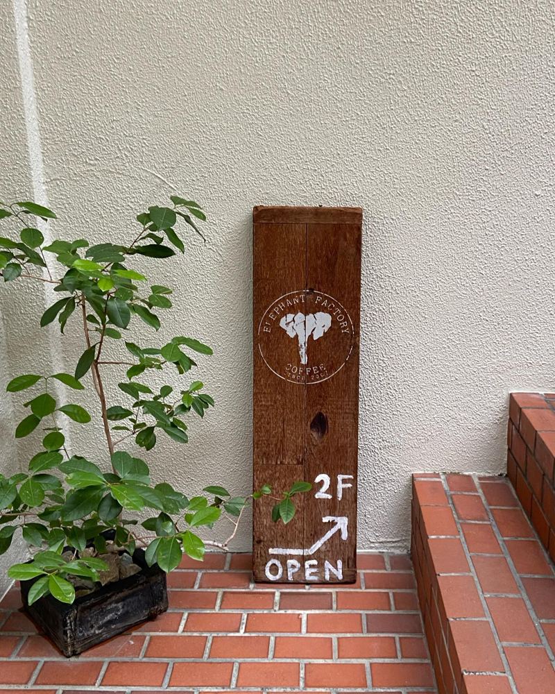 ELEPHANT FACTORY COFFEEの入口に立てかけられた「2F OPEN」の木の看板